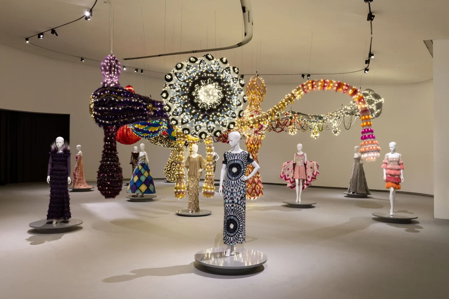 Valentino couture on mannequins beneath Joana Vasconcelos’s illuminated textile installation in the VENUS exhibition at MAAT
