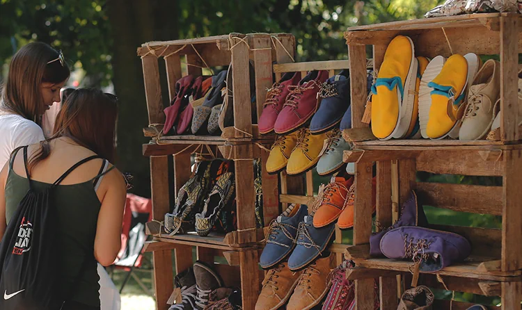 Visitors browsing colourful shoes displayed in wooden crates at the Crafts and Design market