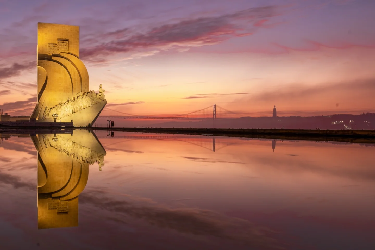 Padrão dos Descobrimentos beside the Tagus at dawn, with the 25 de Abril bridge in the distance.