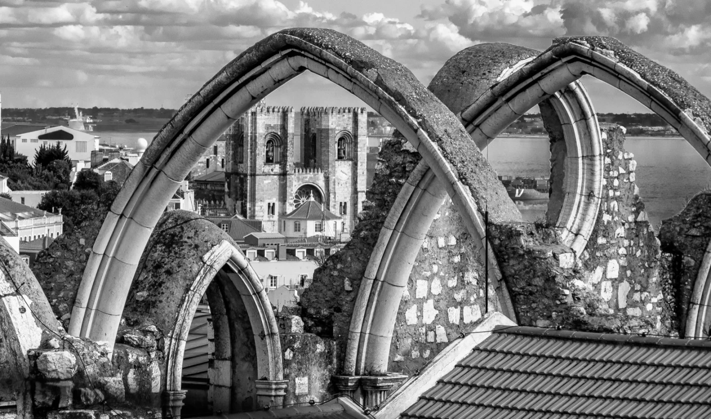 An original black-and-white view through Carmo Convent’s Gothic arches toward Lisbon Cathedral.