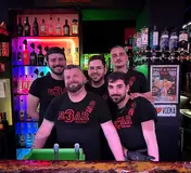 Three people standing at the bar inside TR3S Lisboa
