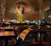 The warmly lit bar, mural and tables inside Mini Bar