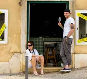 Guests with wine outside the yellow Holy Wine storefront on Calçada da Estrela