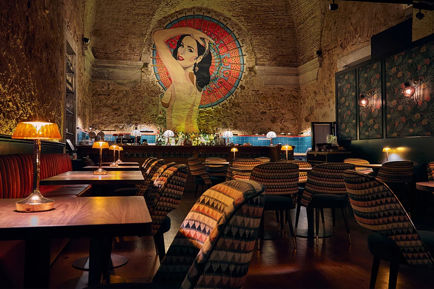 The warmly lit bar, mural and tables inside Mini Bar