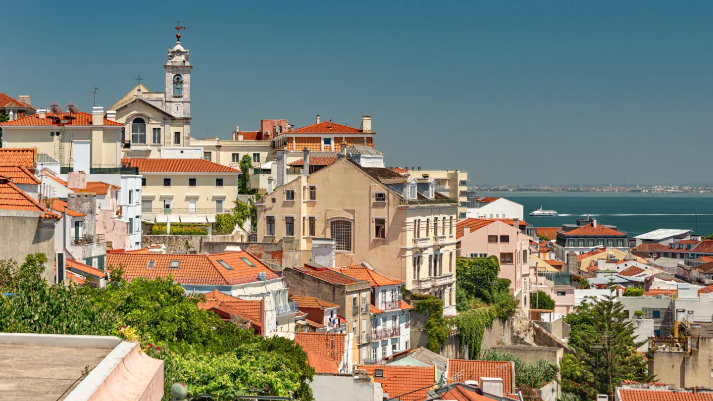 Red-tiled rooftops and Igreja das Chagas de Cristo beside the Tagus, viewed from Miradouro de Santa Catarina in Lisbon.