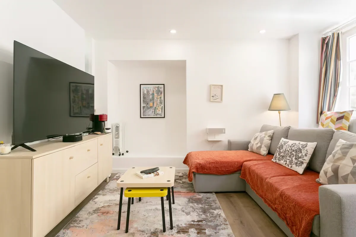 The apartment’s living room with its sofa, TV and warm decor