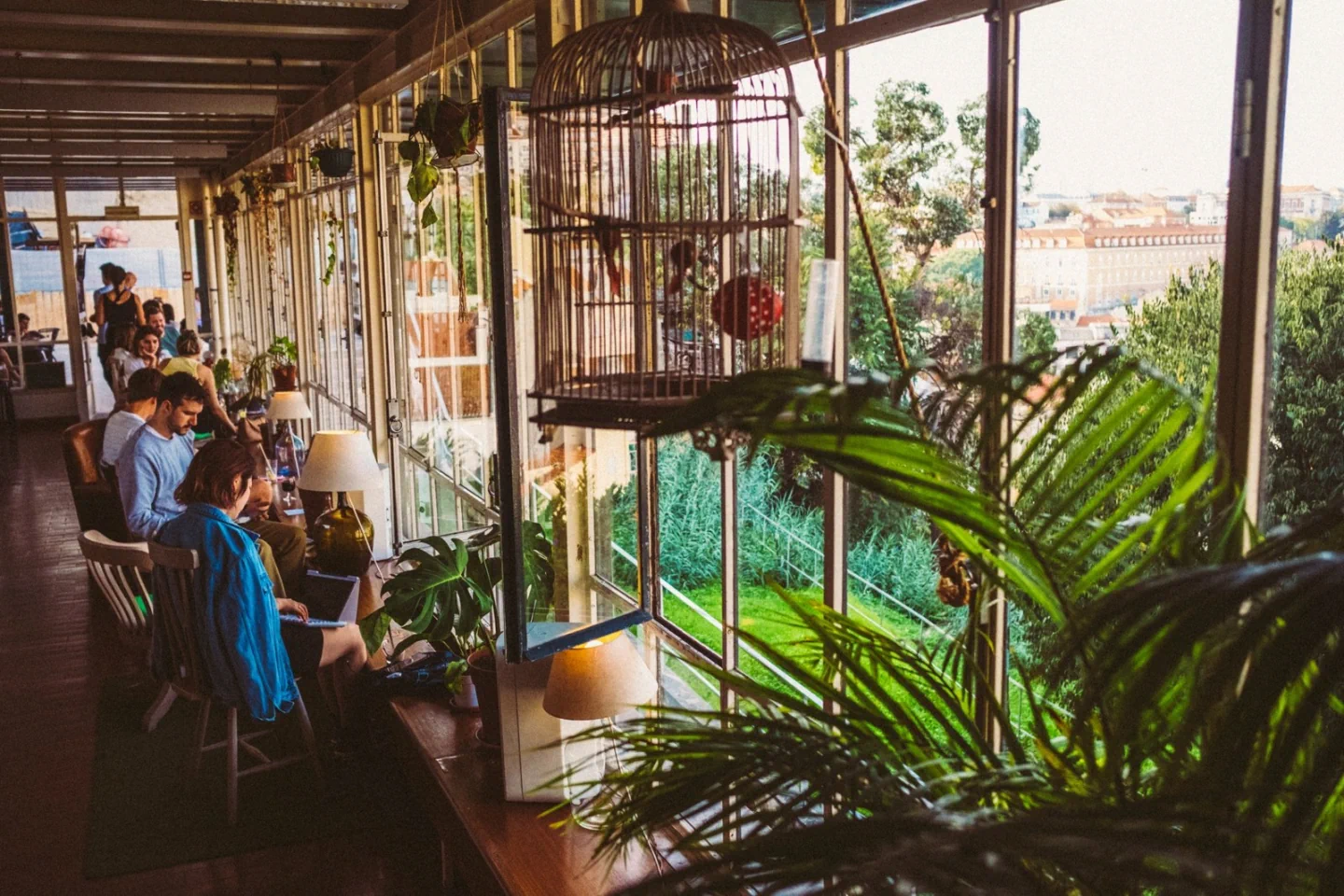 Plants and café tables beside the windows at Café da Garagem