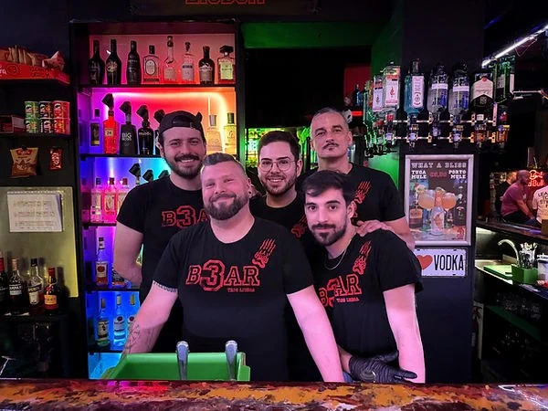 Three people standing at the bar inside TR3S Lisboa